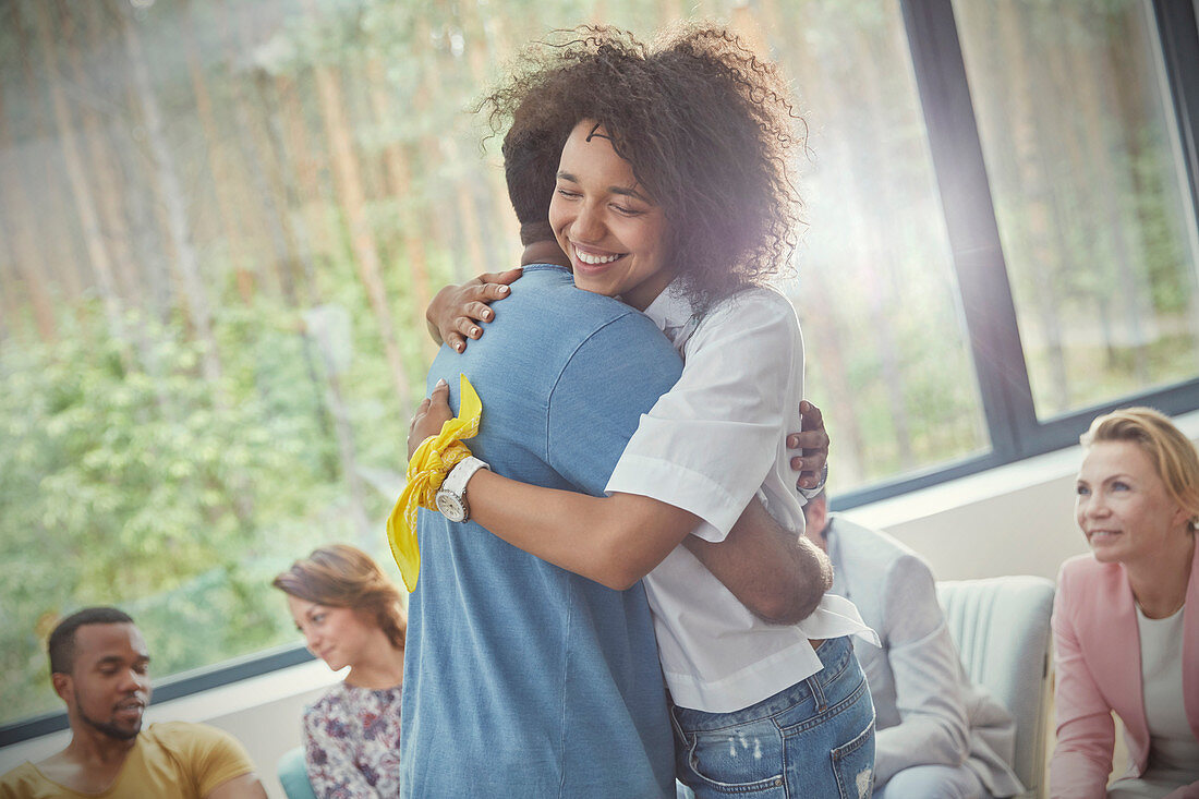 Smiling woman hugging man in group therapy session