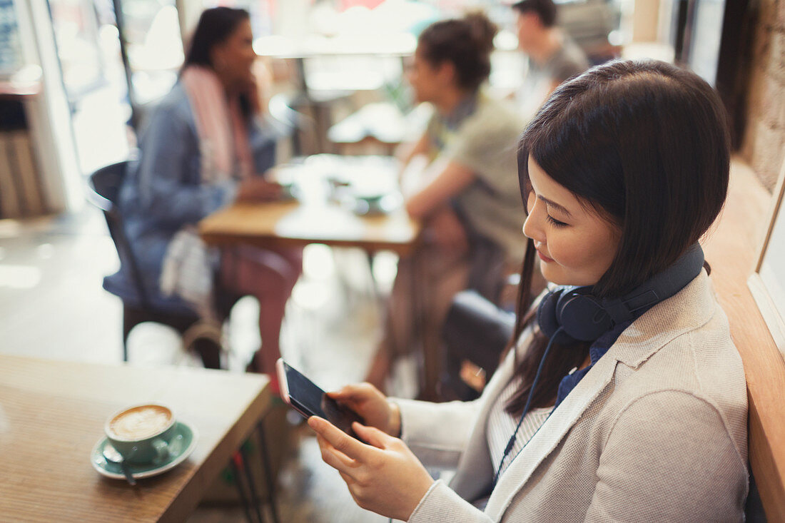 Young woman texting and drinking coffee