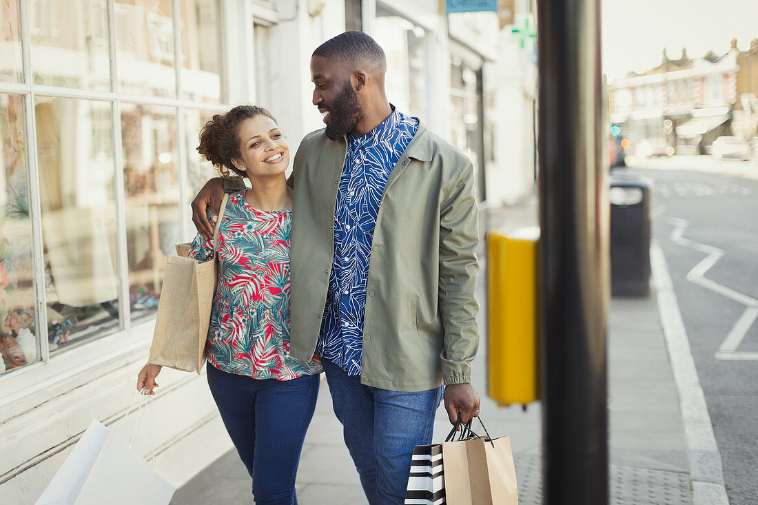 Affectionate couple walking along urban storefront
