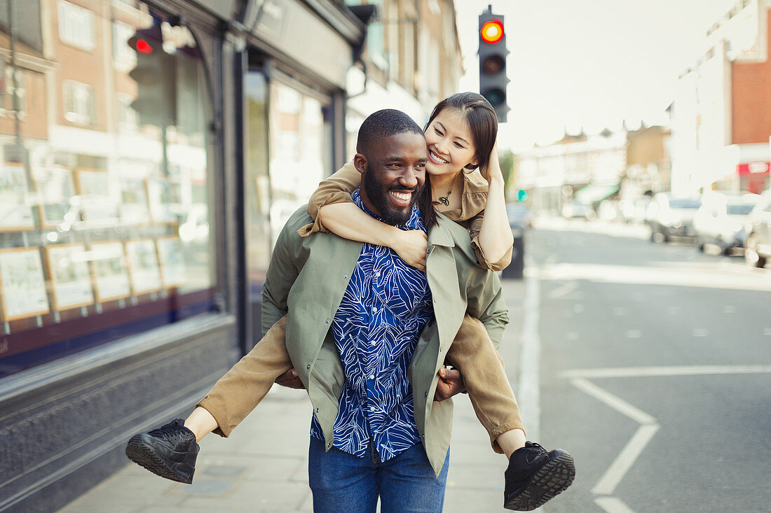 Playful couple piggybacking on urban street