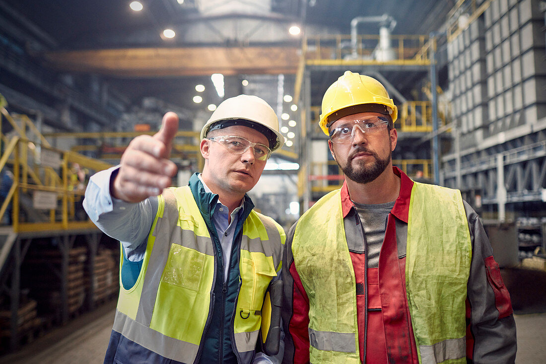 Steelworkers talking, gesturing in steel mill