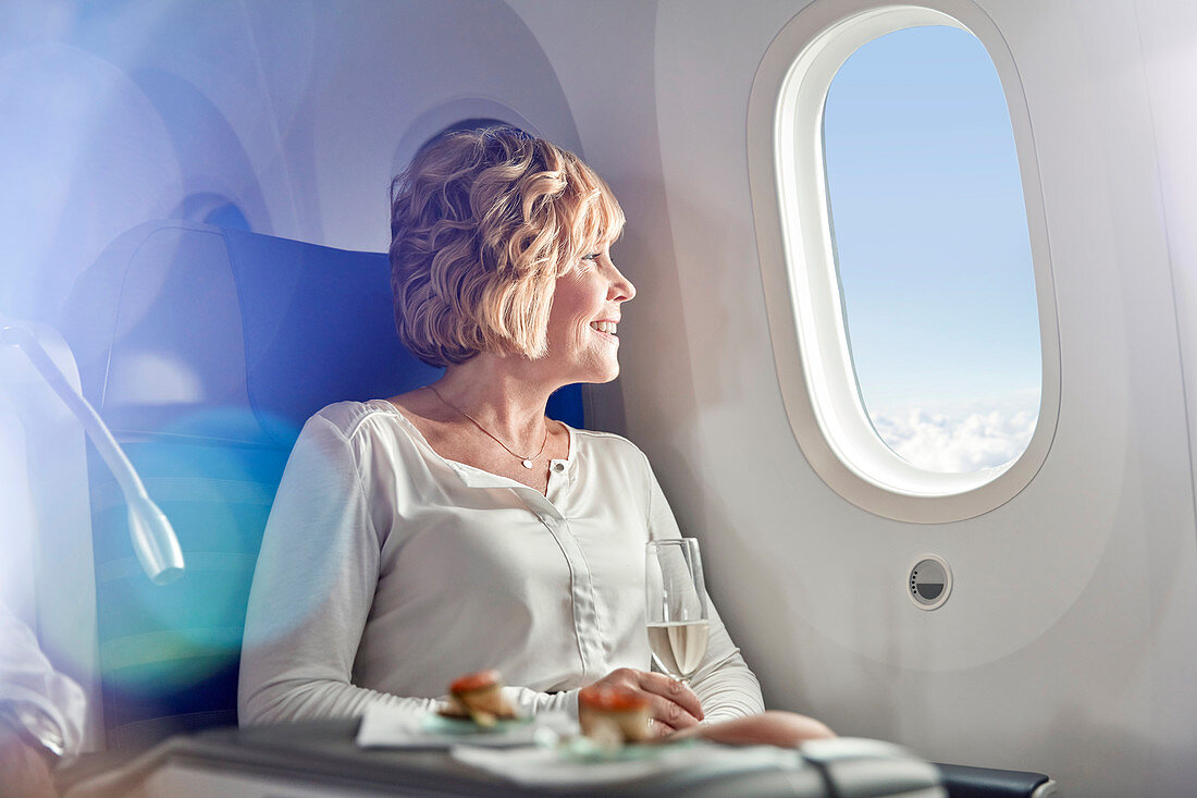 Smiling woman drinking champagne on airplane