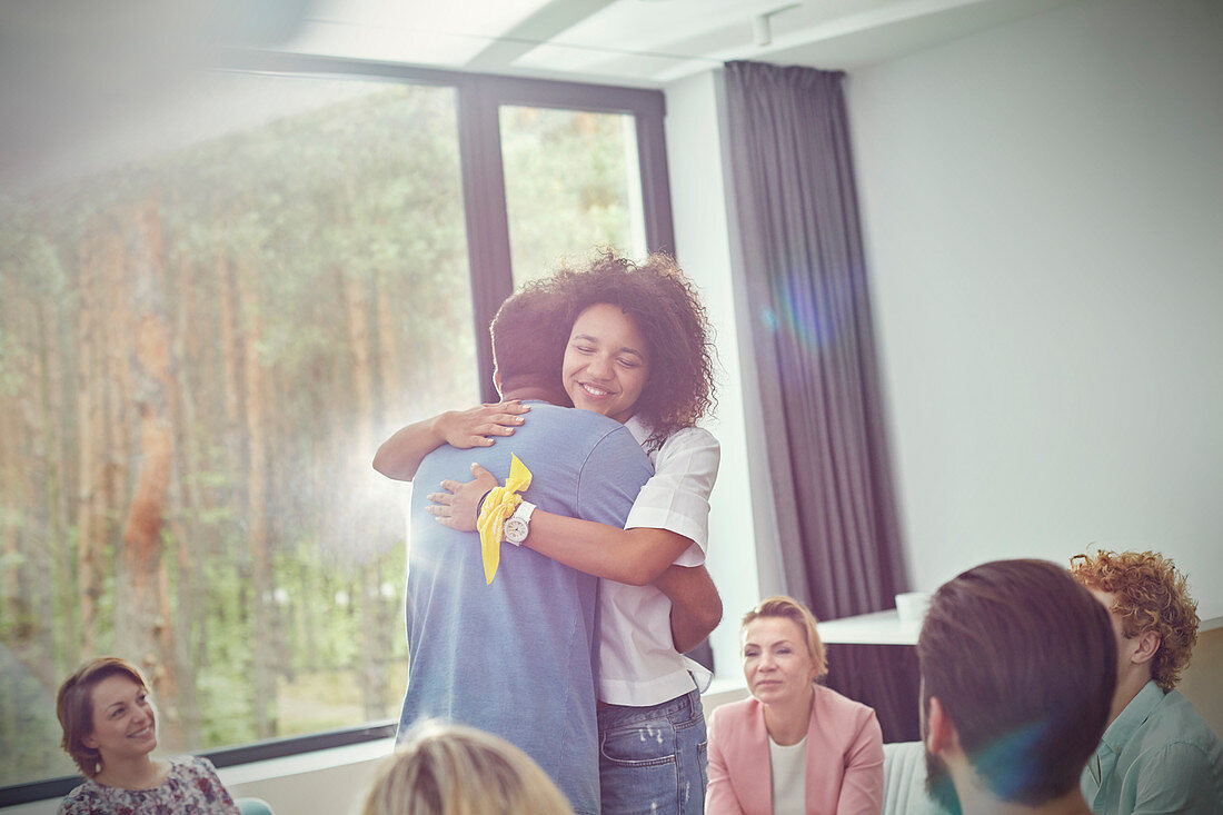 Man and woman hugging in group therapy session