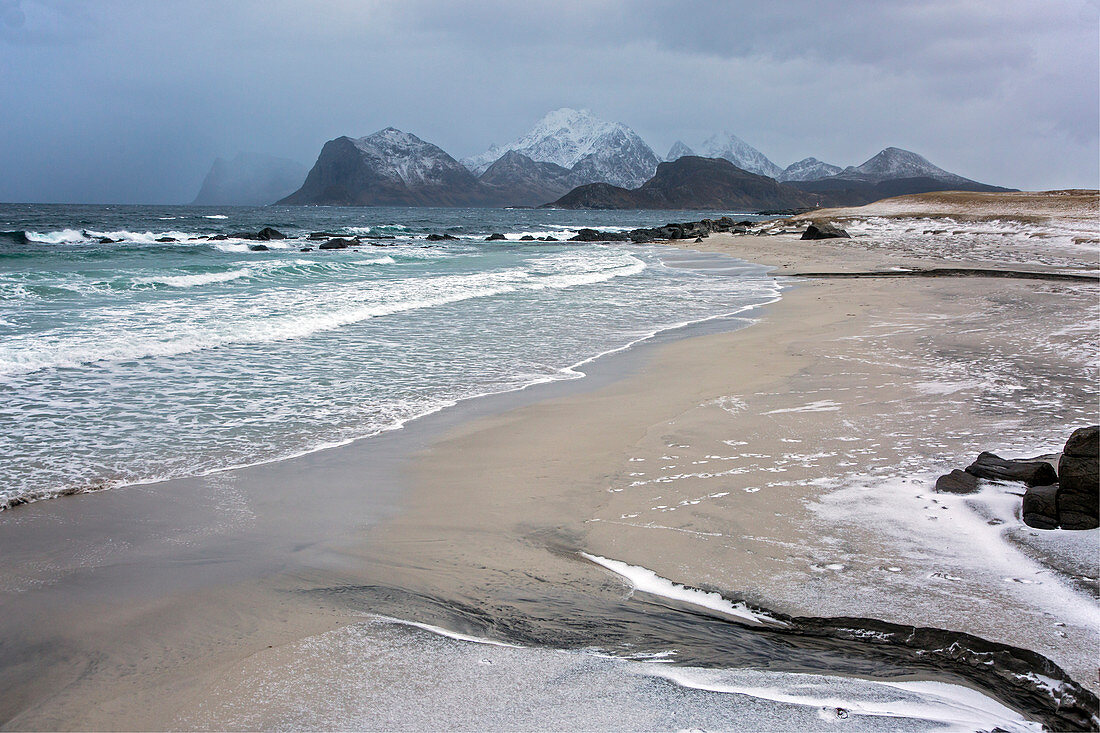 Rugged mountains behind ocean beach, Norway