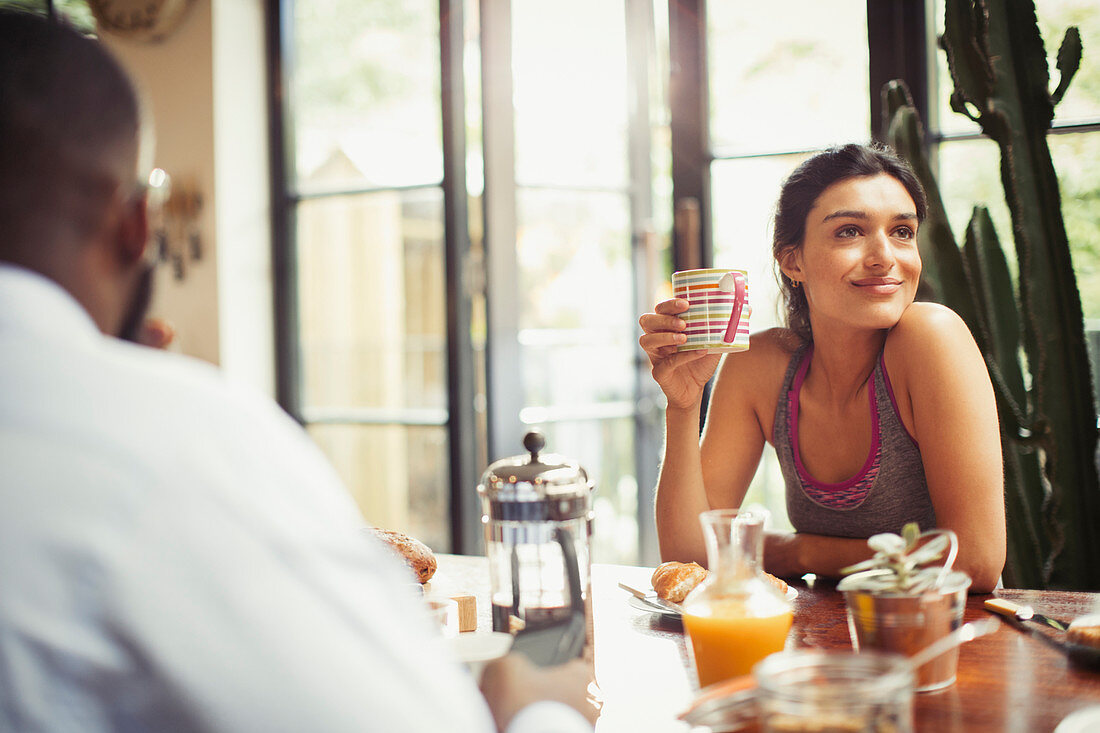 Smiling woman drinking coffee at breakfast table