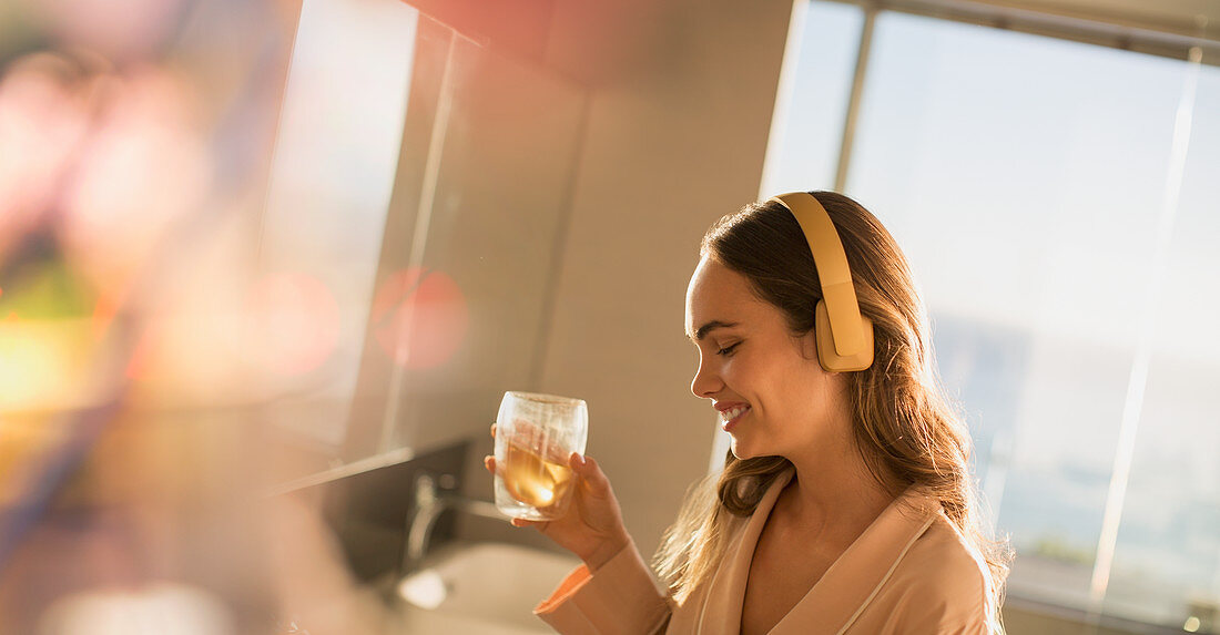 Smiling woman listening to music and drinking