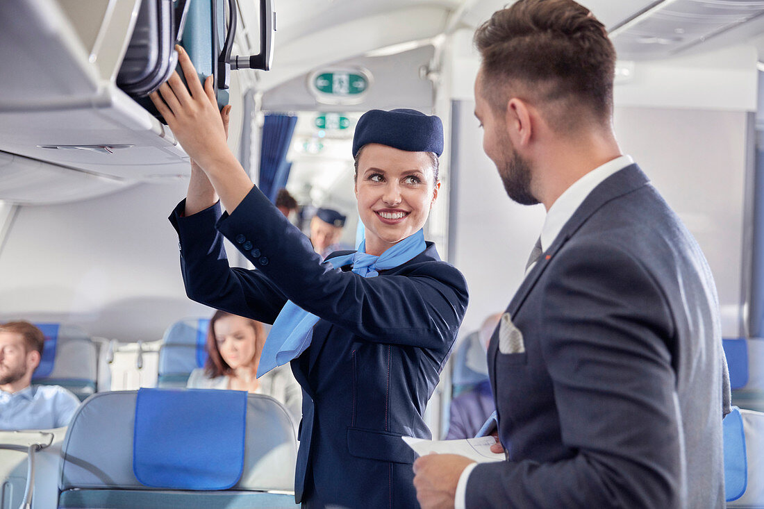 Flight attendant helping businessman with luggage