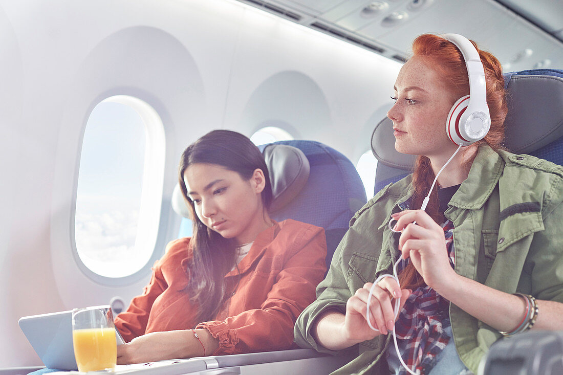 Young women friends and digital tablet on airplane