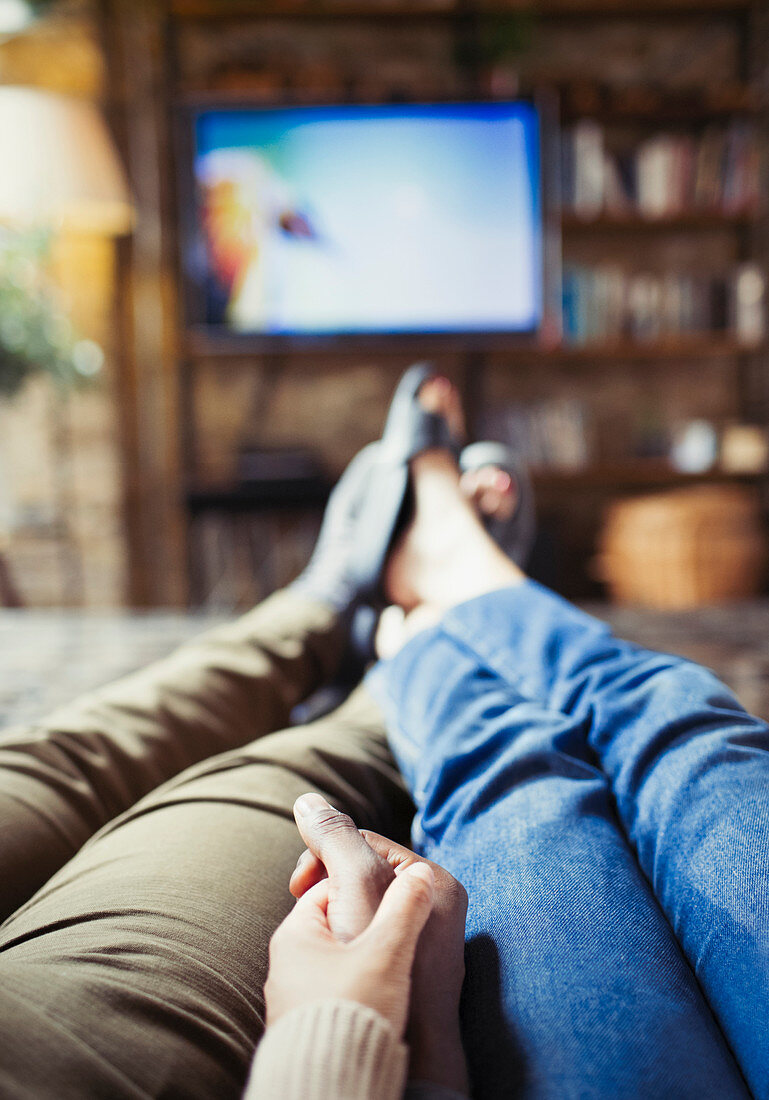 Couple holding hands watching TV