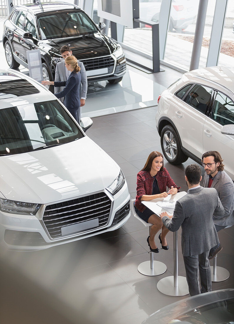 Car sales people meeting at table in showroom