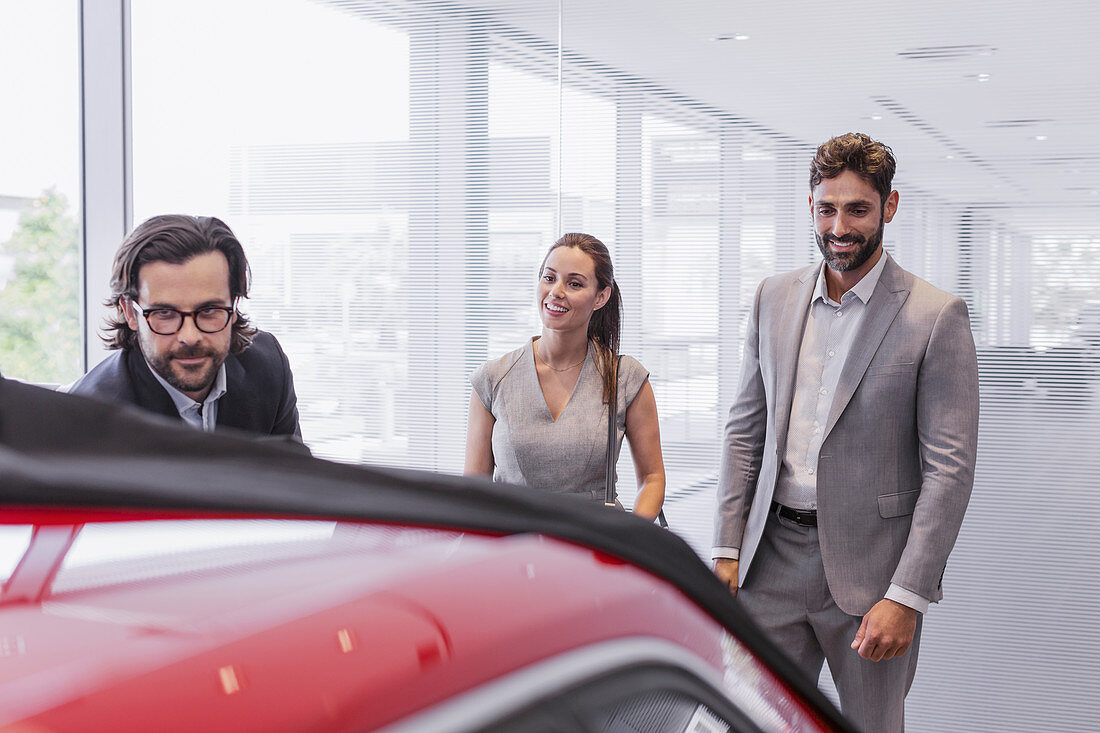 Car salesman showing car to couple customers