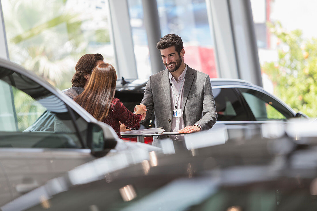 Car salesman handshaking with customers