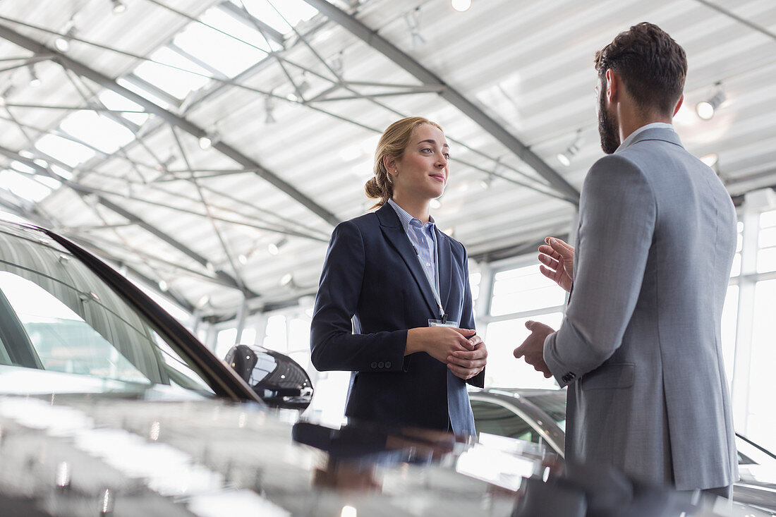 Car saleswoman talking to customer in showroom