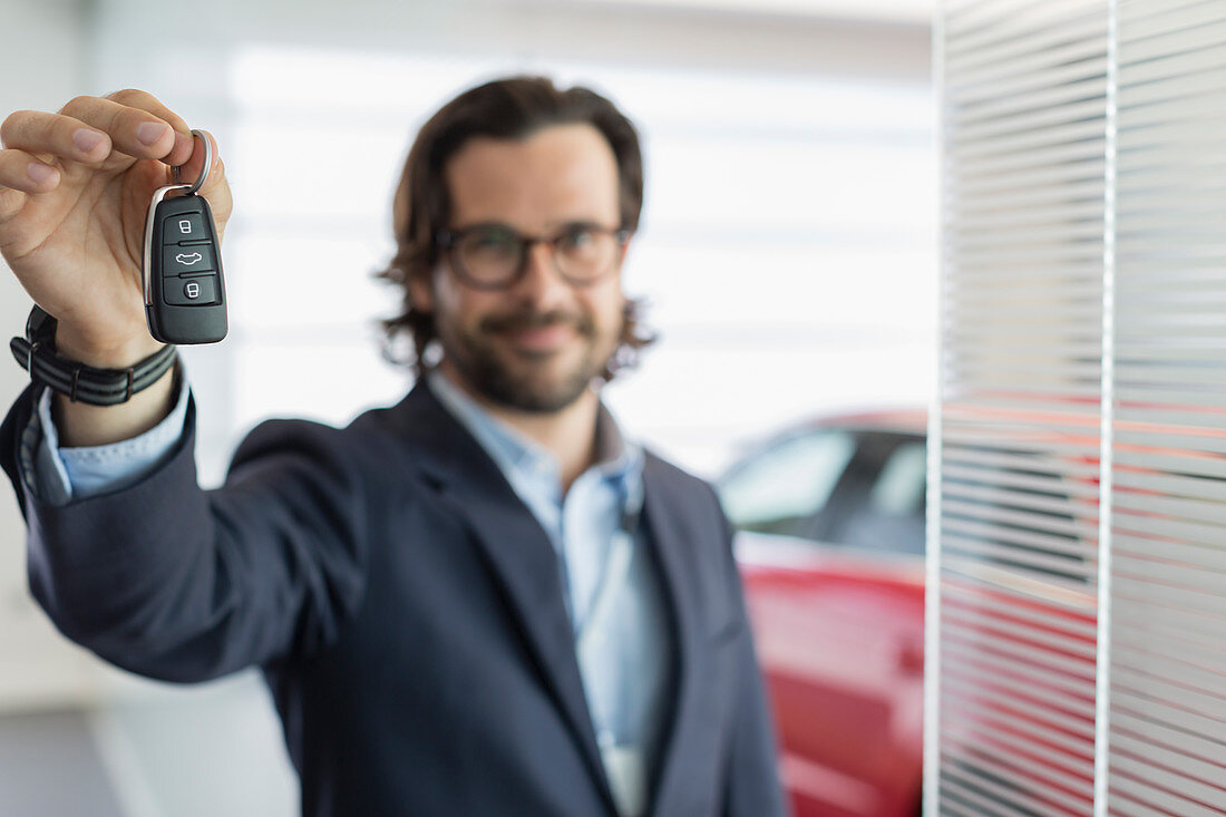 Portrait car salesman holding, showing car key