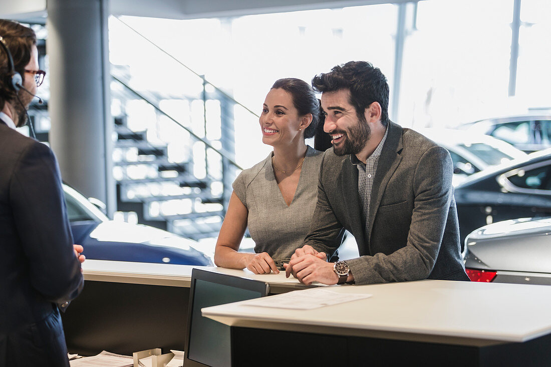 Couple customers talking to receptionist at desk