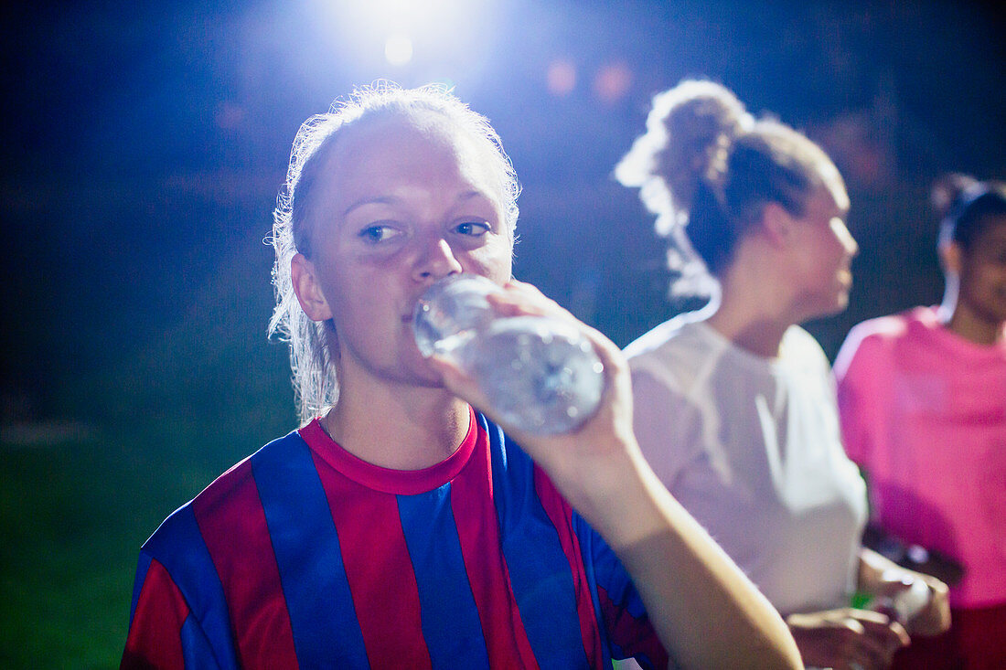 Young soccer player drinking from water bottle