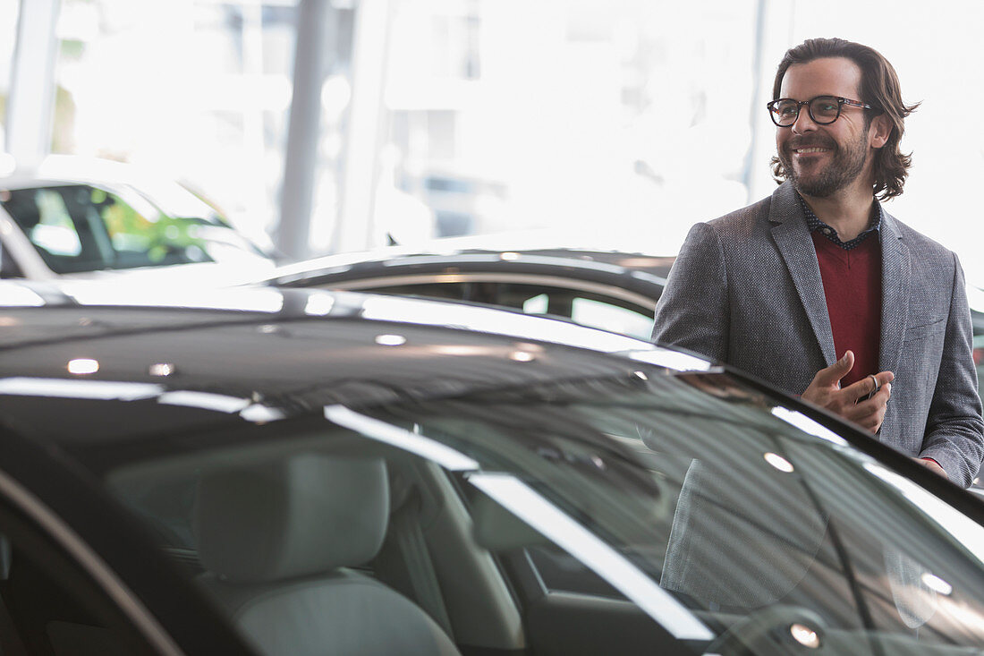 Smiling man browsing at cars in showroom