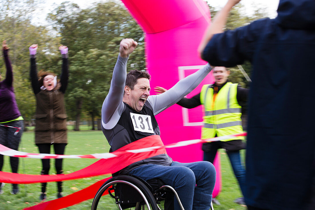 Man in wheelchair crossing race finish line