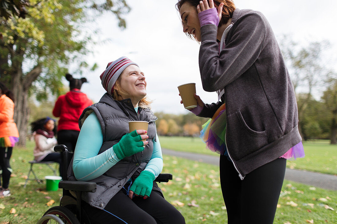 Woman in wheelchair talking to friend in park