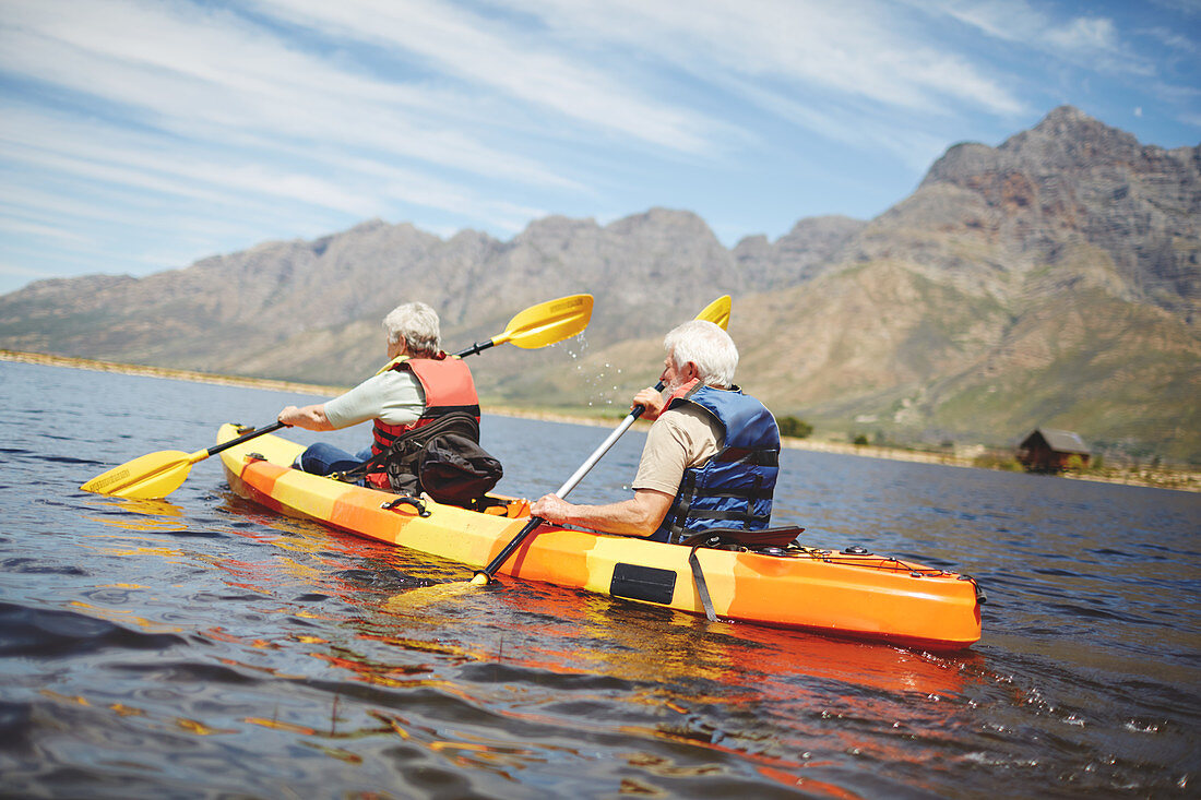 Active senior couple kayaking in sunny summer lake