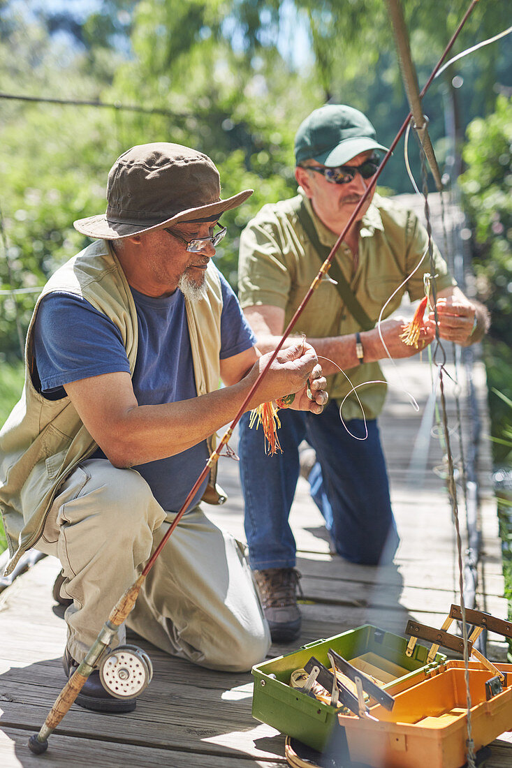 Active senior male friends preparing fishing lines