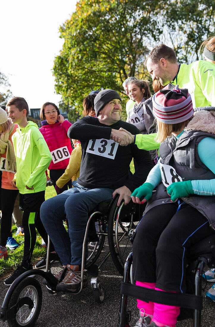 Man in wheelchair shaking hands with runner