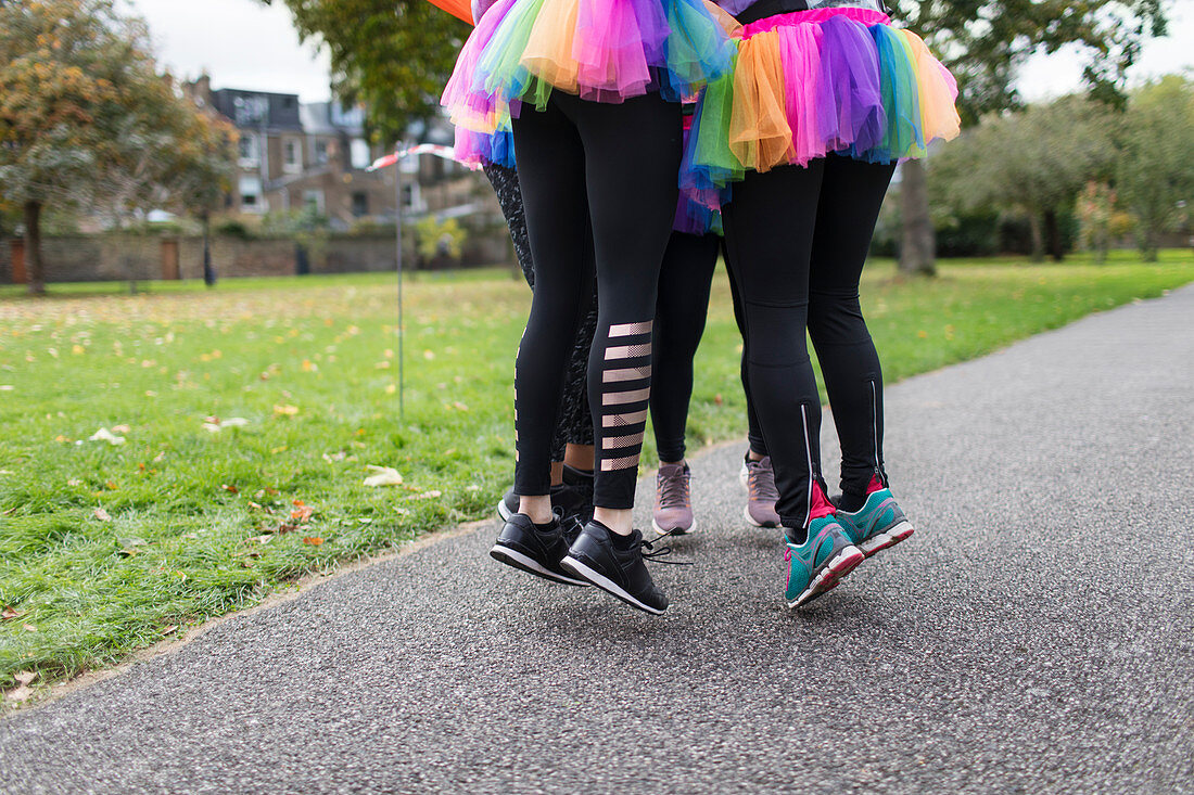 Enthusiastic runners in tutus jumping on park path