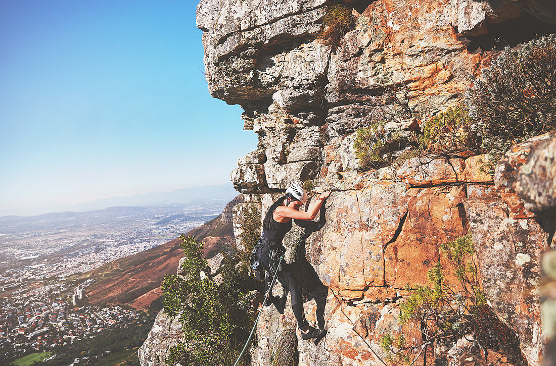 Female rock climber hanging from rock