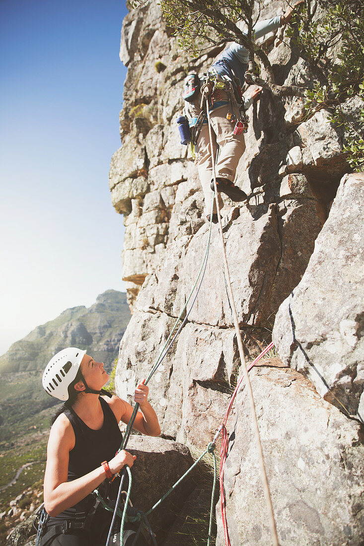 Female rock climber holding ropes for partner