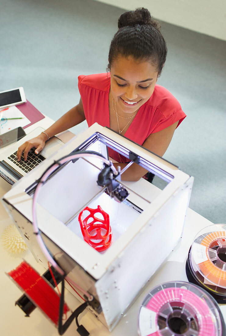 Smiling female designer watching 3D printer
