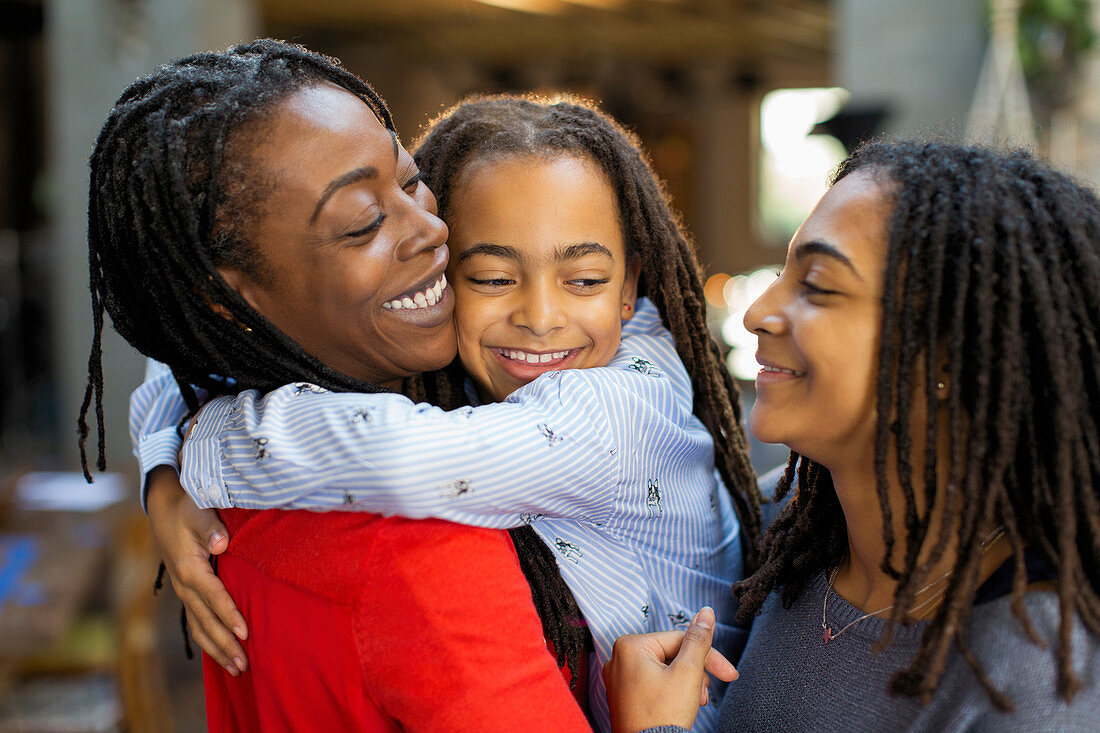 Affectionate mother and daughters hugging