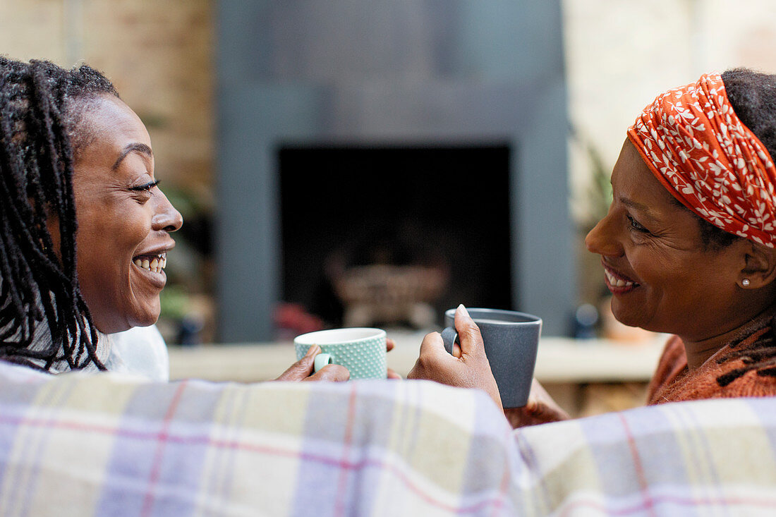 Smiling women friends talking and drinking tea