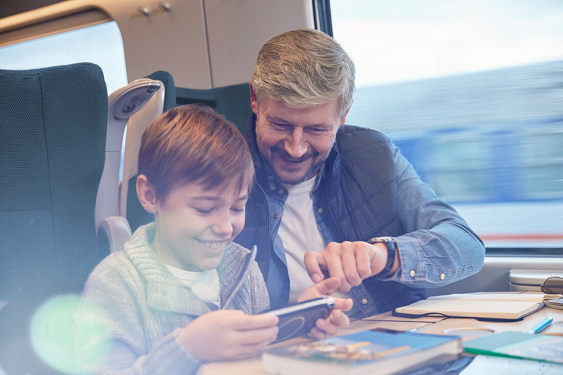 Father and son using smart phone on train