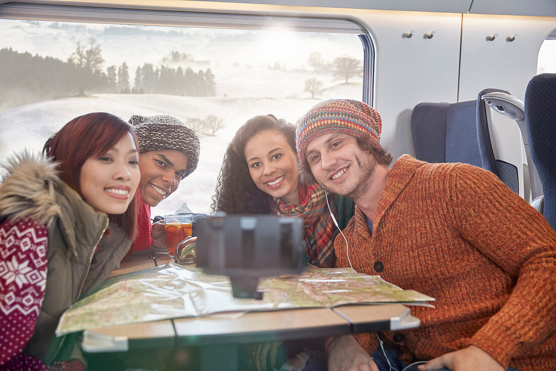 Young friends with map taking selfie on train
