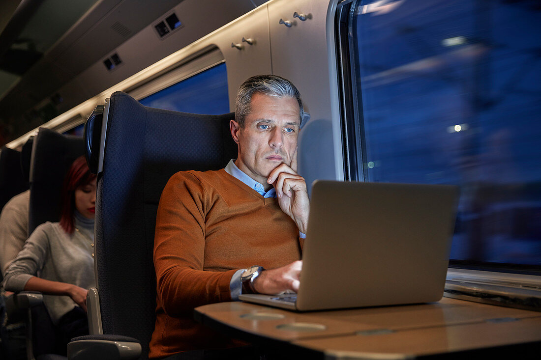 Focused businessman working at laptop on train