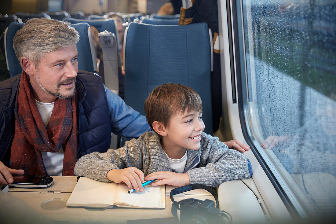 Father and son looking out window on train