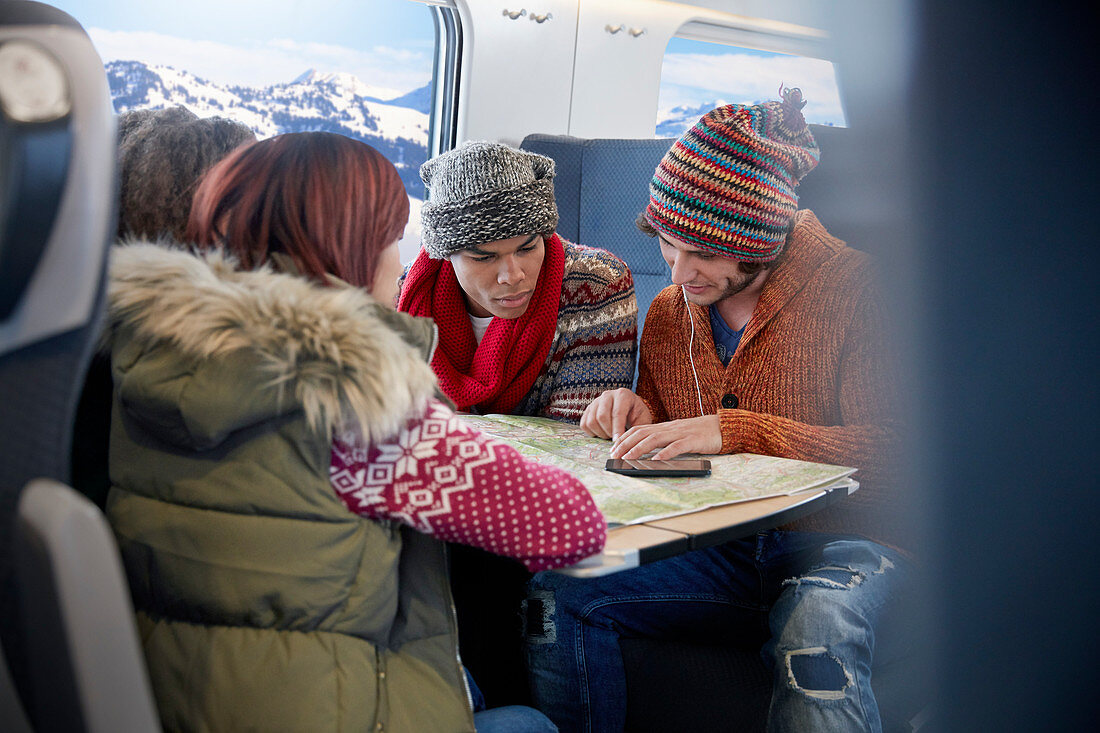 Young friends with map planning on train