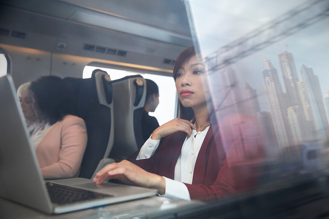 Focused businesswoman working at laptop on train