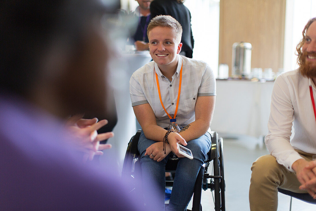 Woman in wheelchair talking to colleagues in conference