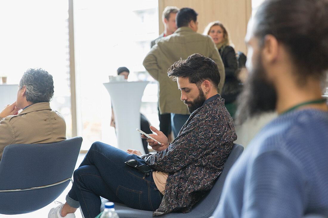 Businessman texting in conference audience