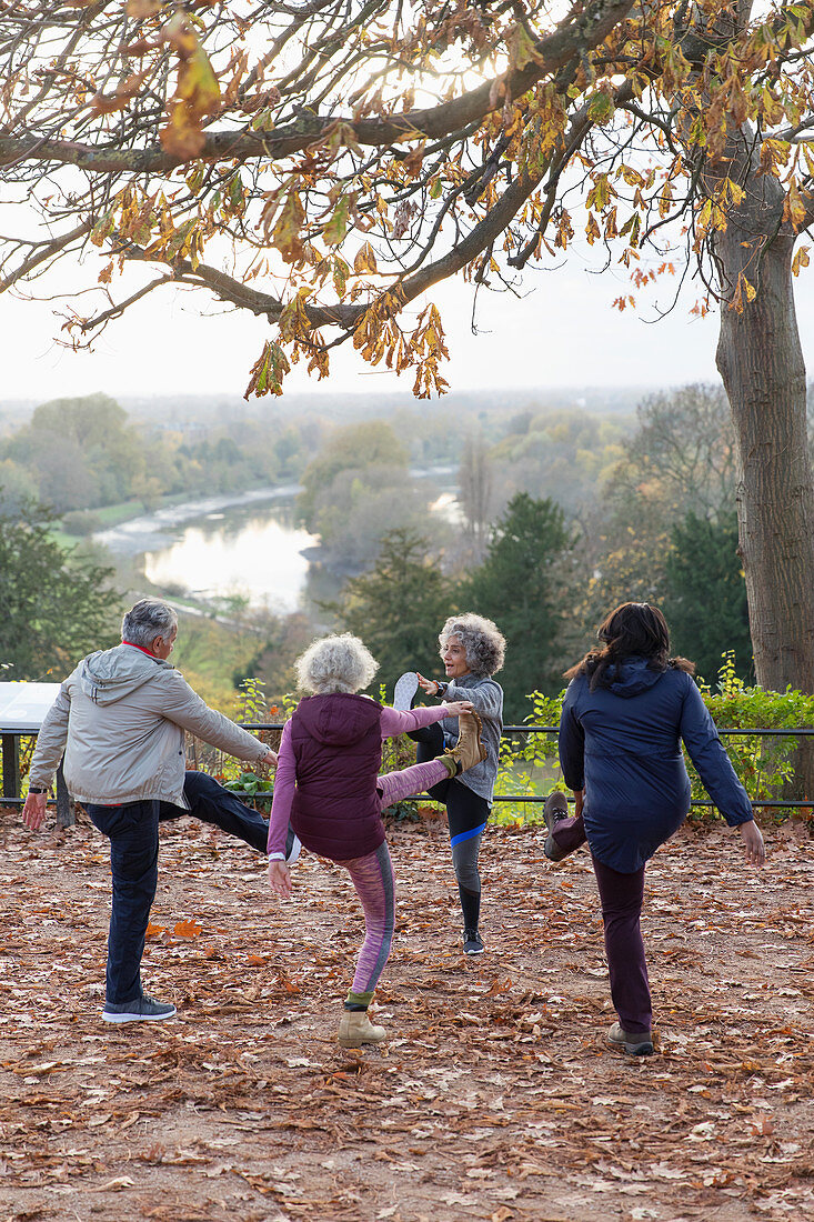 Active seniors stretching, exercising in autumn park