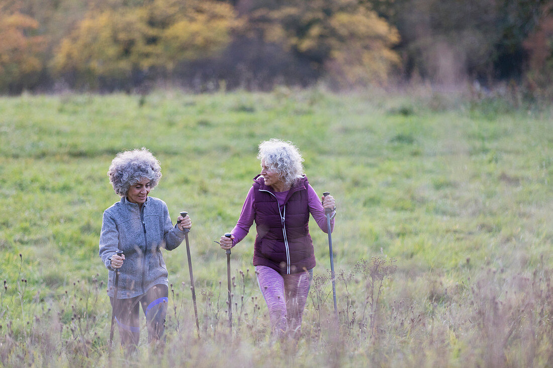 Active senior women friends hiking with poles