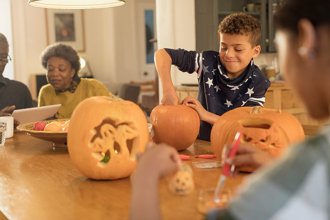 Boy carving Halloween pumpkins at table