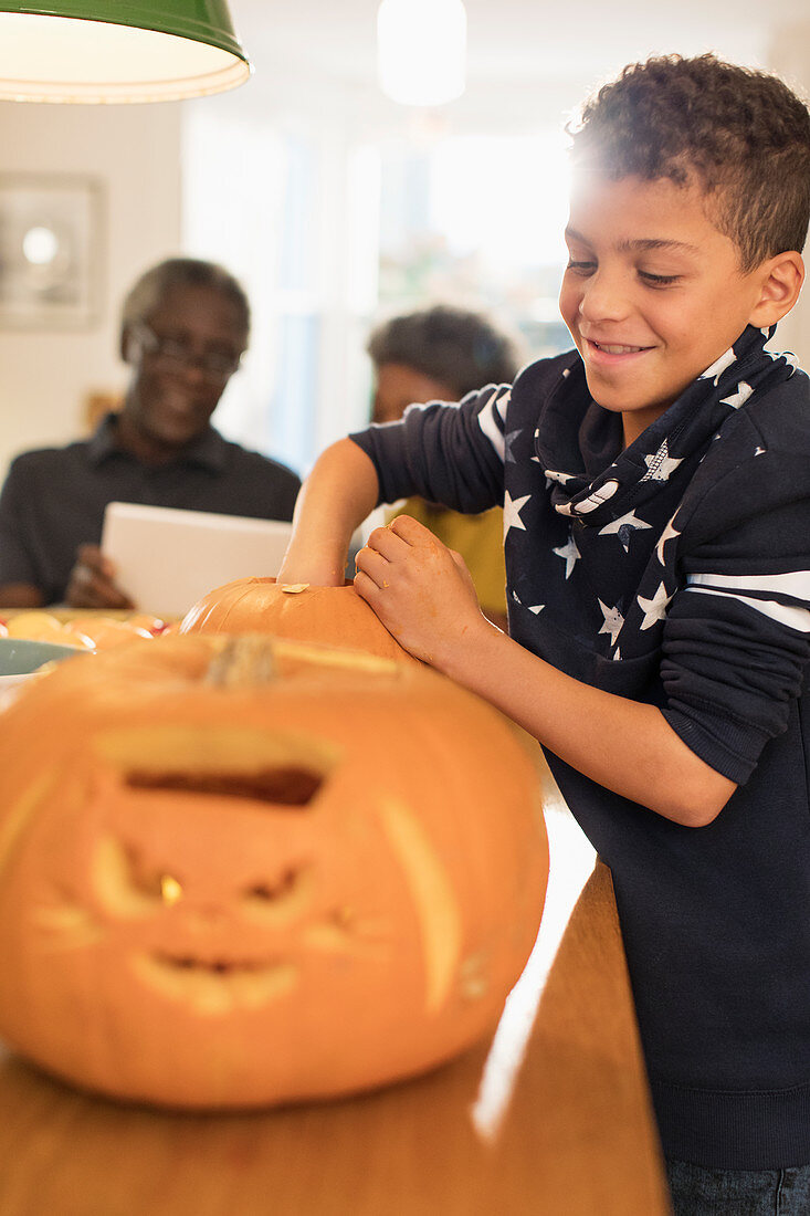 Smiling boy carving Halloween pumpkins