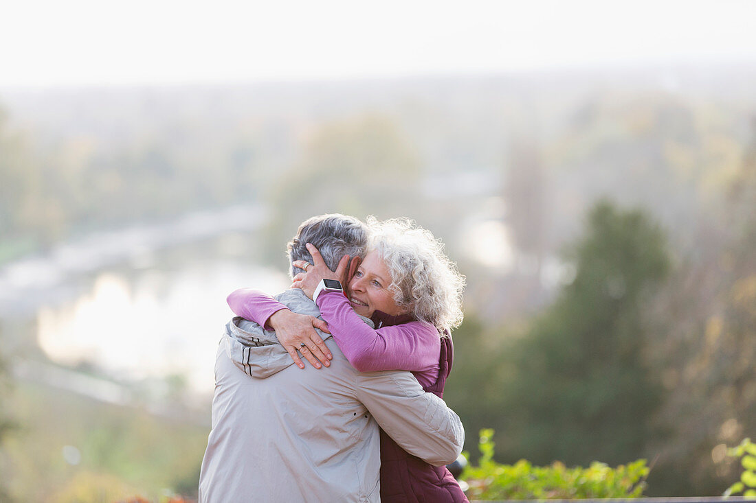 Affectionate active senior couple hugging in nature