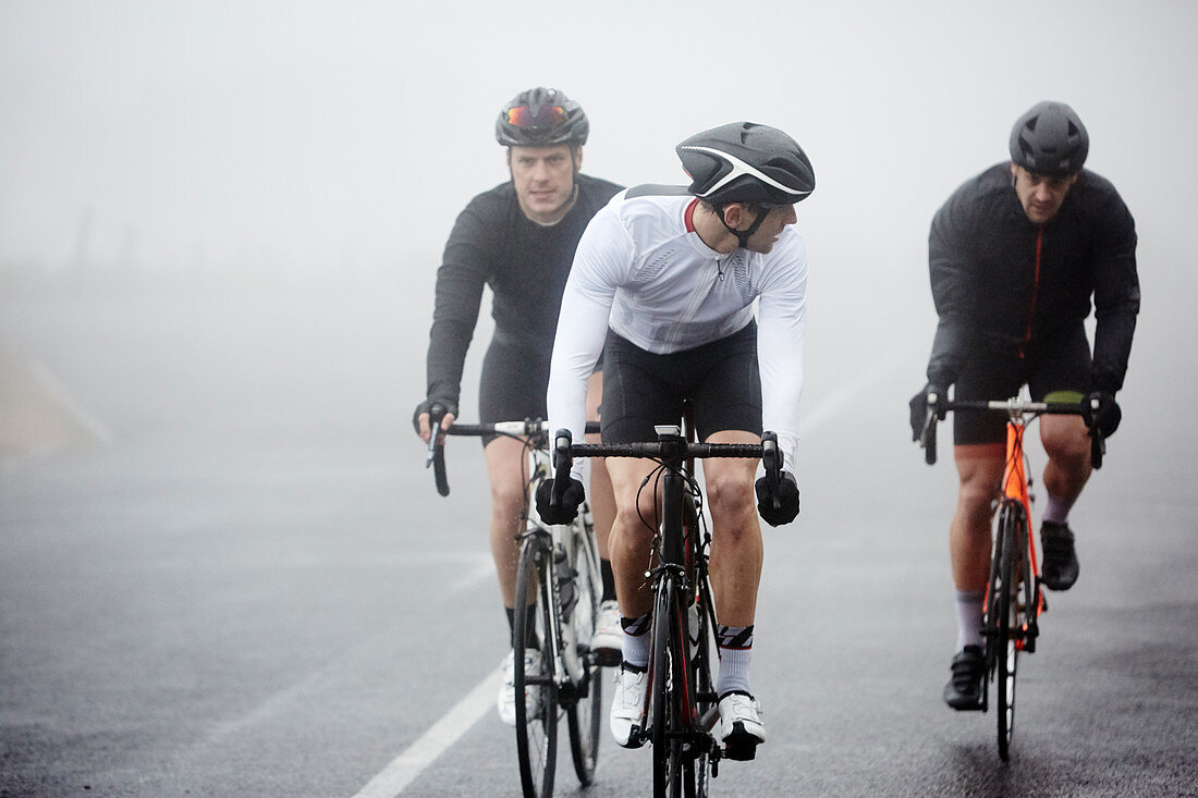 Dedicated male cyclists cycling on rainy road