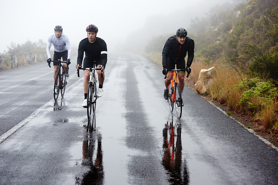 Male cyclists cycling on wet road