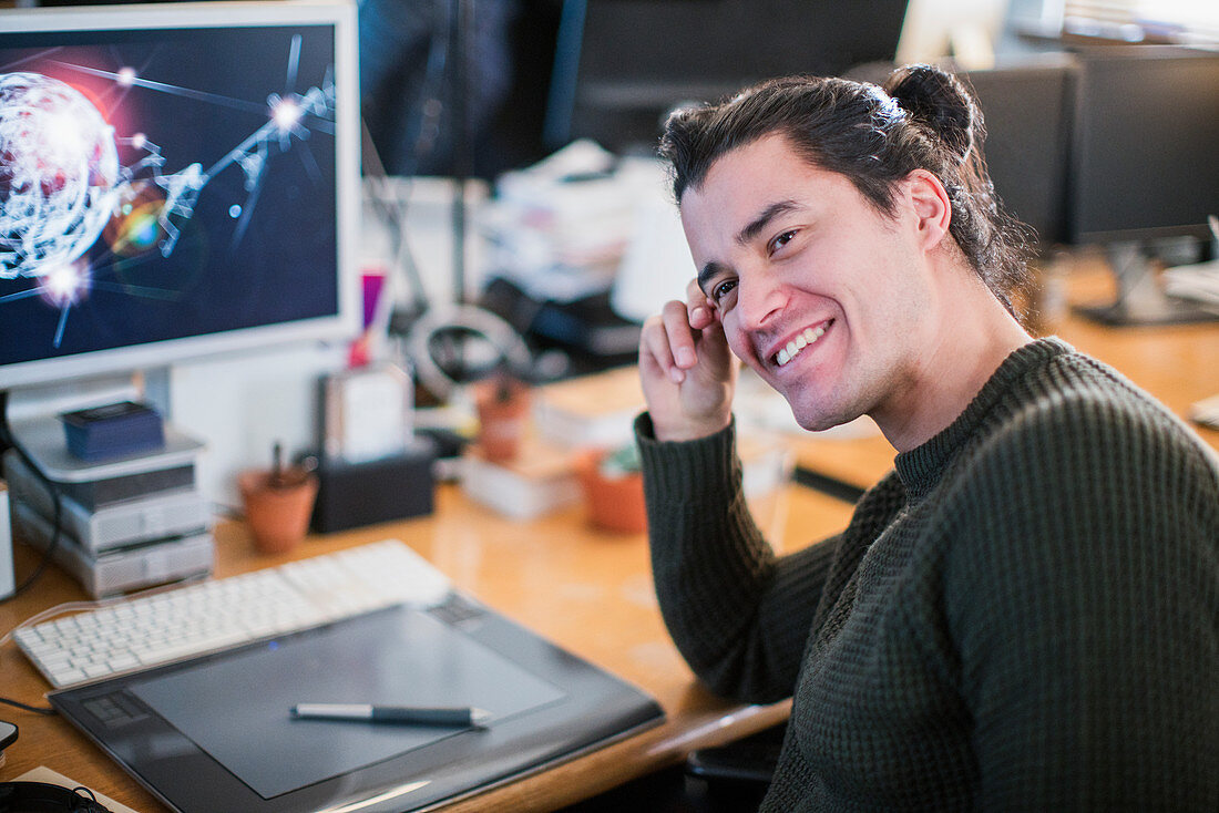 Portrait smiling male graphic designer working at desk