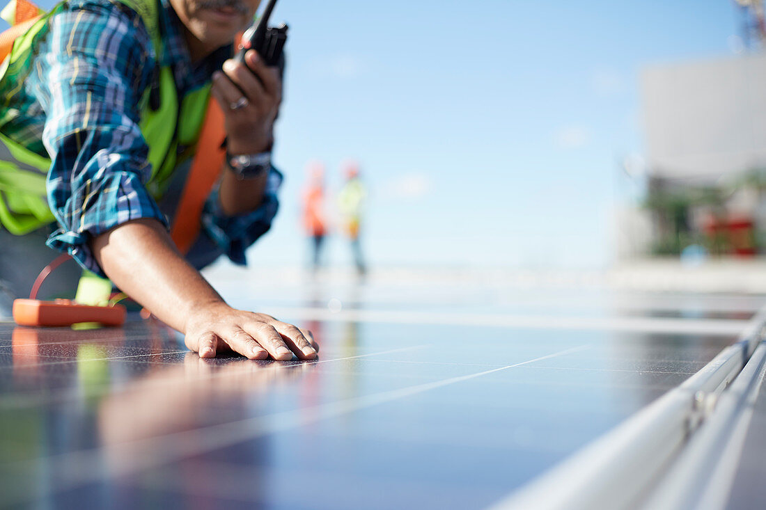 Engineer with walkie-talkie inspecting solar panels