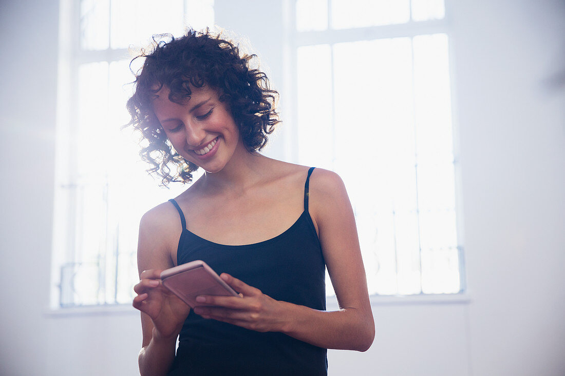 Smiling young female dancer texting with smart phone